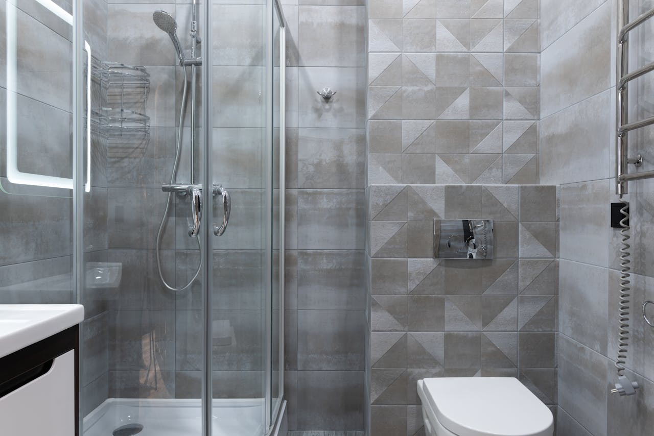 gallery-3 Contemporary bathroom featuring a sleek glass shower and geometric tiled walls.