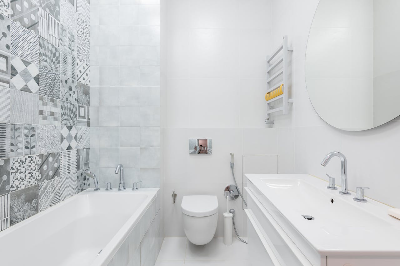 gallery-6 Contemporary bathroom featuring white sanitaryware, a round mirror, and patterned wall tiles for a sleek design.